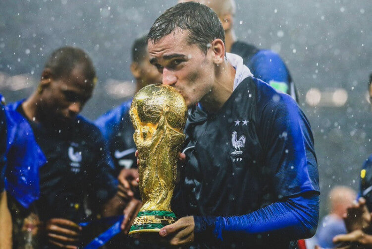 Antoine Griezmann sedang mencium dan memegang Piala Dunia di tahun 2018